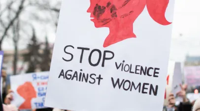 Woman holding up a sign that says "stop violence against women"